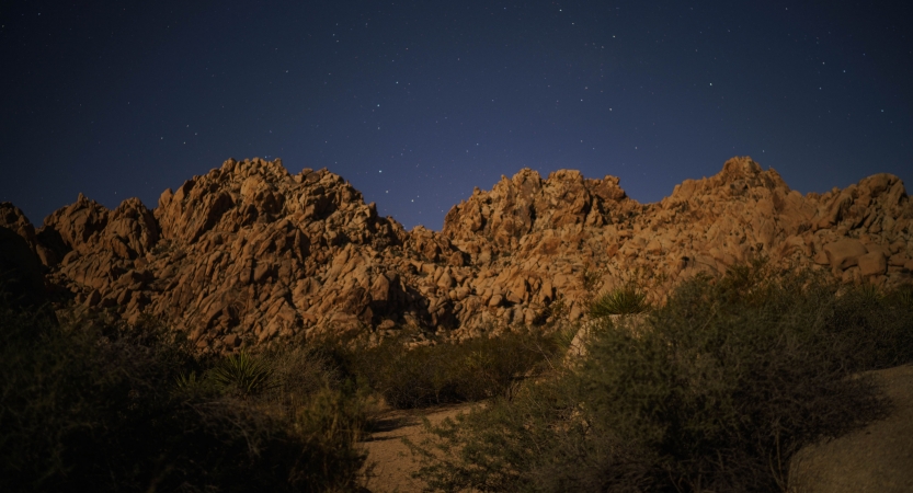 a large rock formation juts upwards towards the night sky, dotted with stars